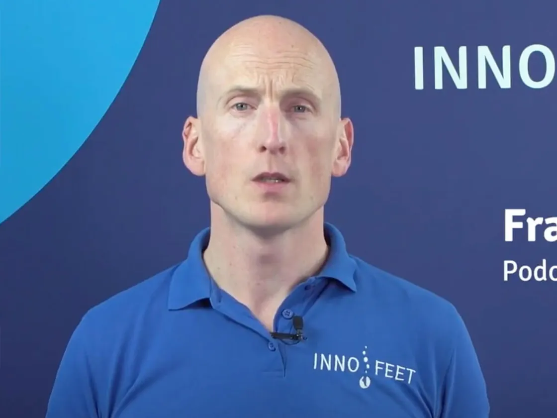 Presentator in een Innofeet-polo voor een blauwe achtergrond